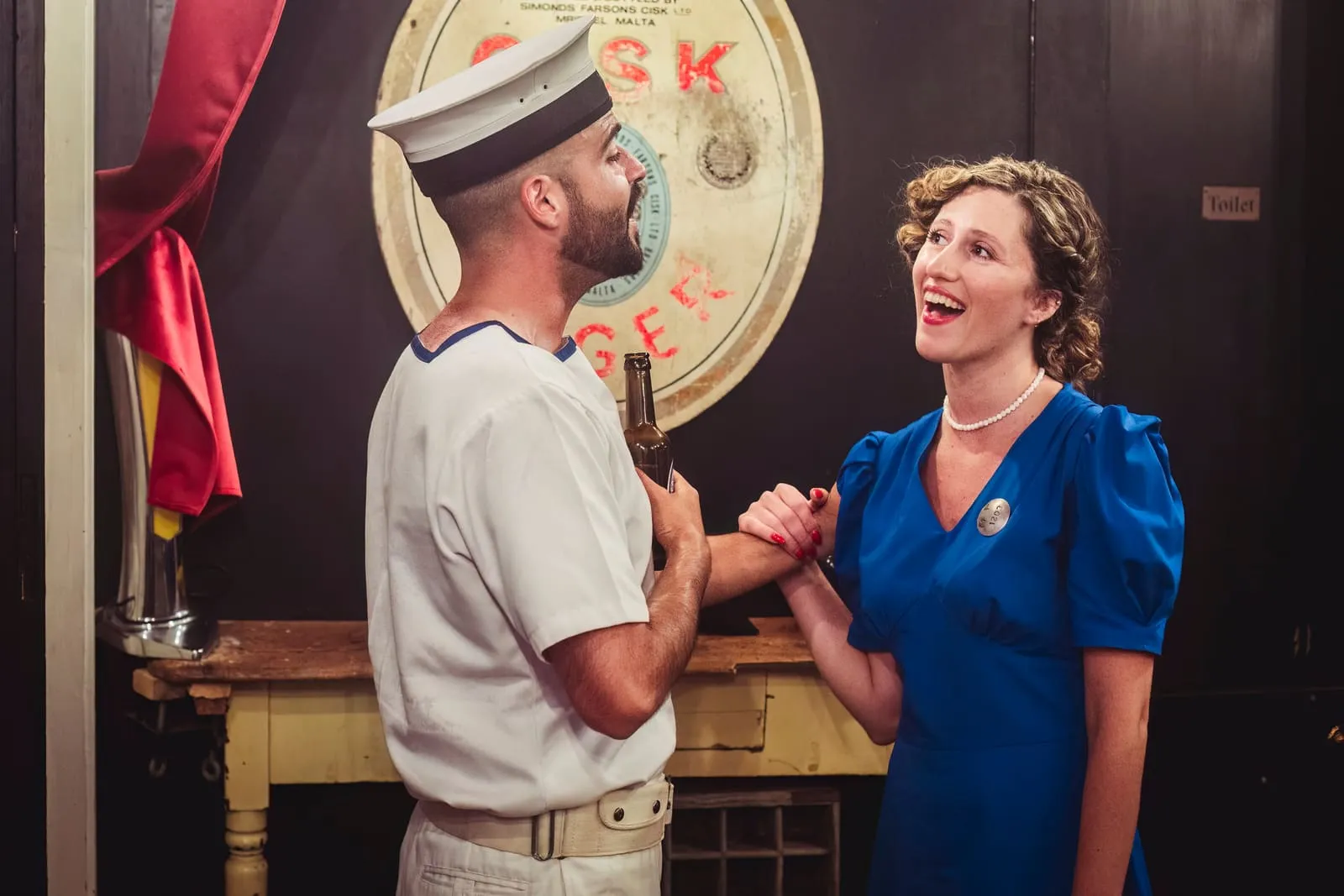 The sailor and the barmaid singing to one another, hand in hand.