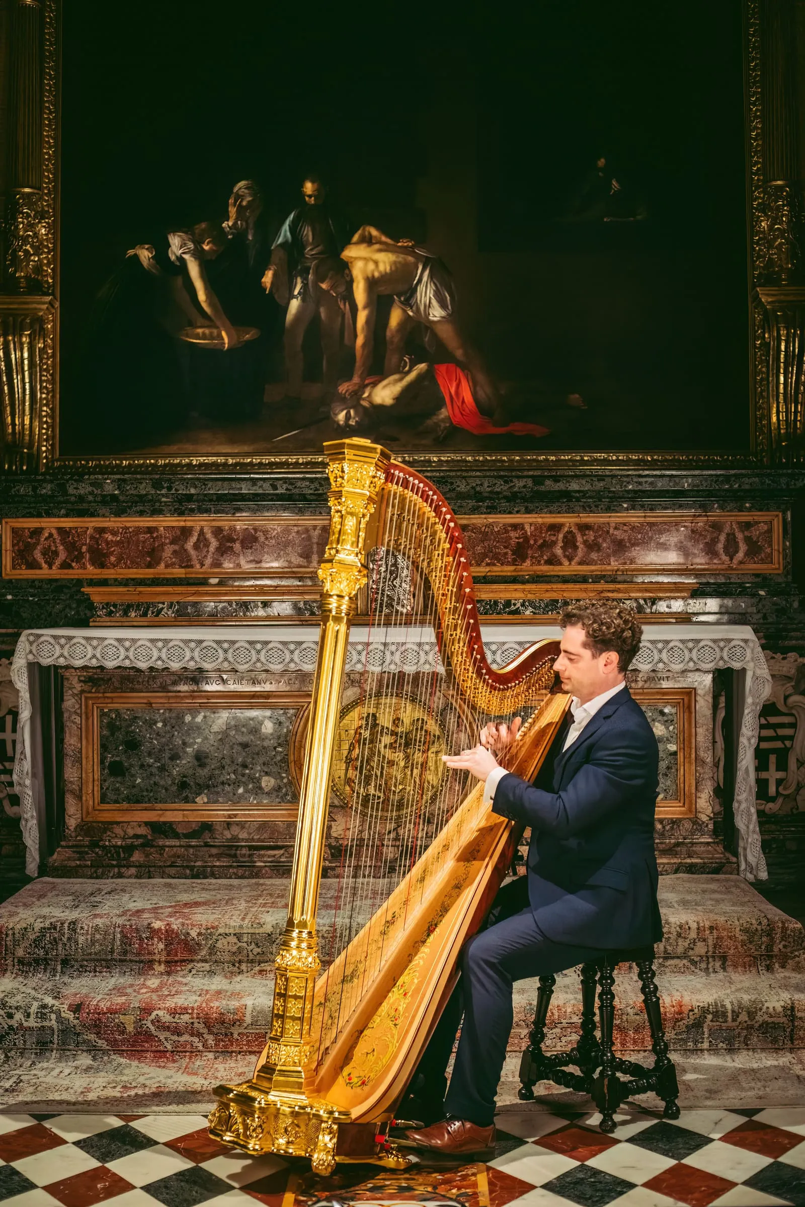 A musician at the gilded Baroque harp before the marble altar of the Oratory.